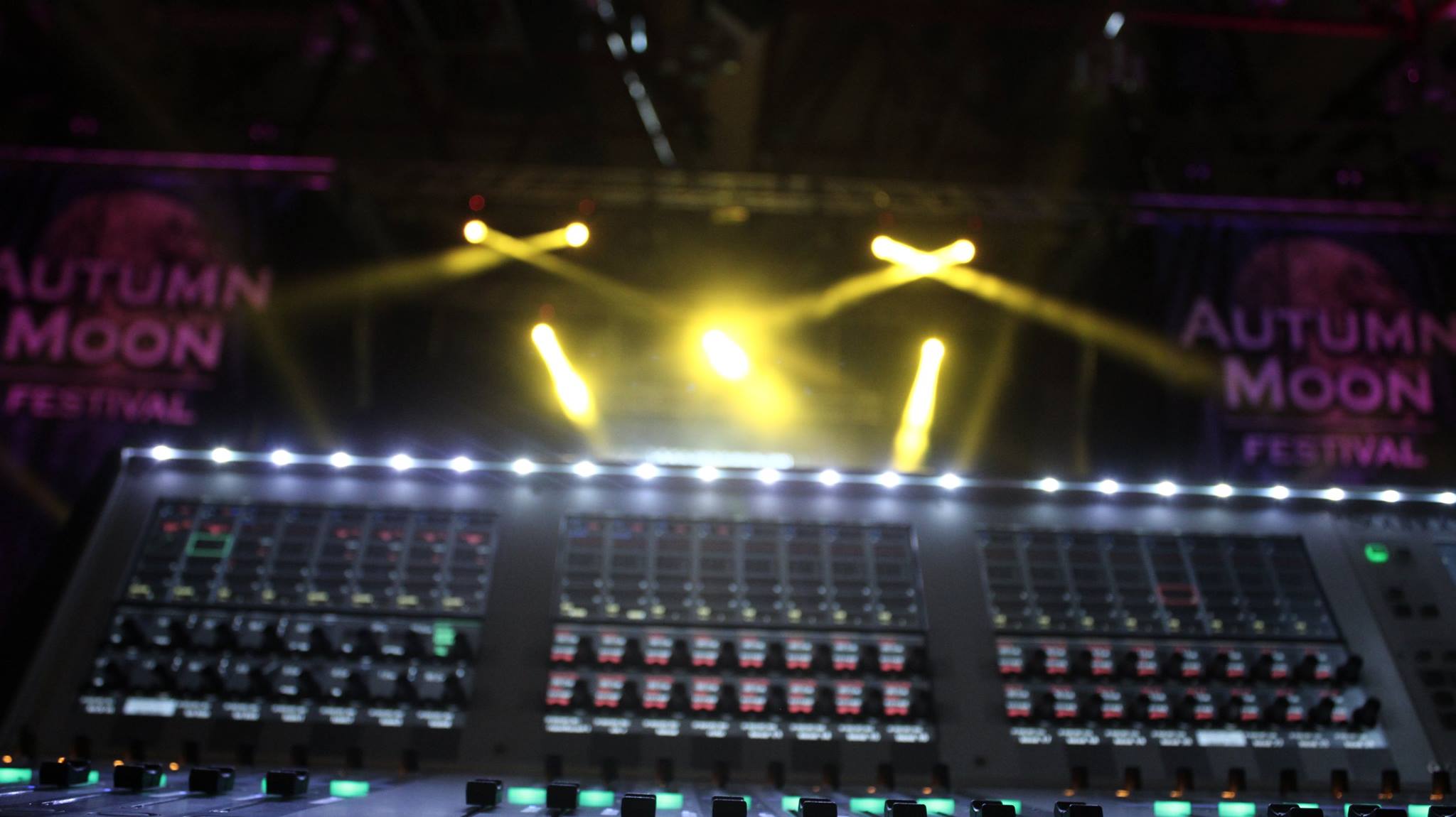 Mischpult vor der Autumn-Moon-Festivalbühne mit gelben Lichtstrahlen